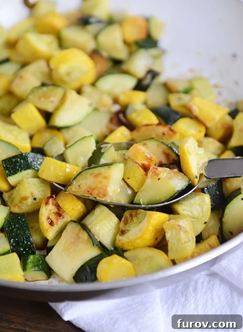 A plate full of sautéed zucchini and yellow squash, with a full spoonful of the saute on top of the mixture. 