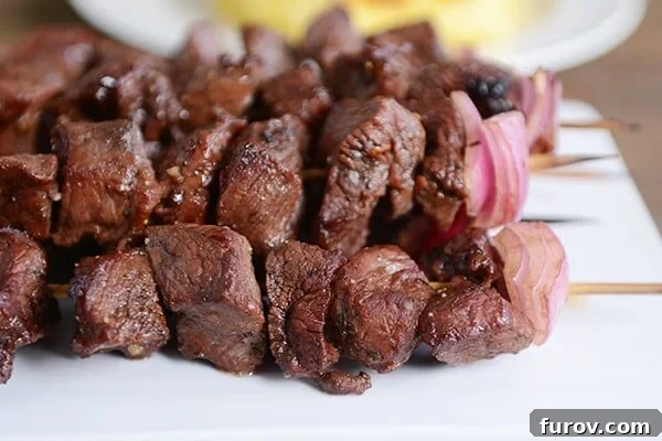A white tray of cooked balsamic beef kebabs, showcasing a perfect sear and tender texture.