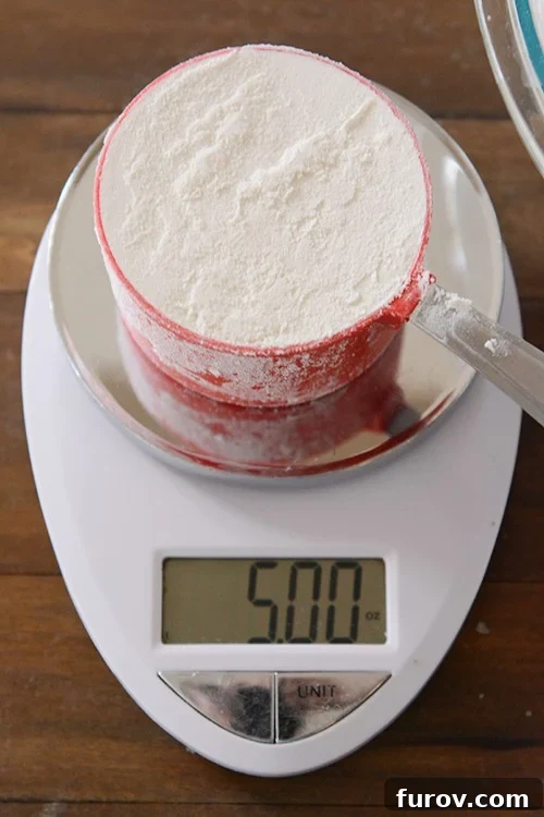 a measuring cup full of flour getting weighed on a kitchen scale