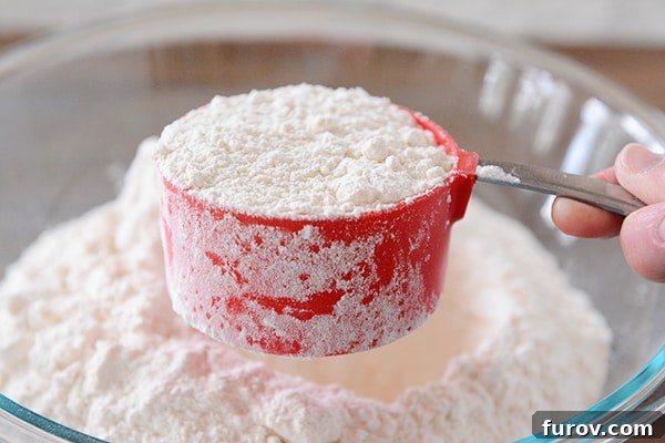 Side view of a red measuring cup full of flour. 