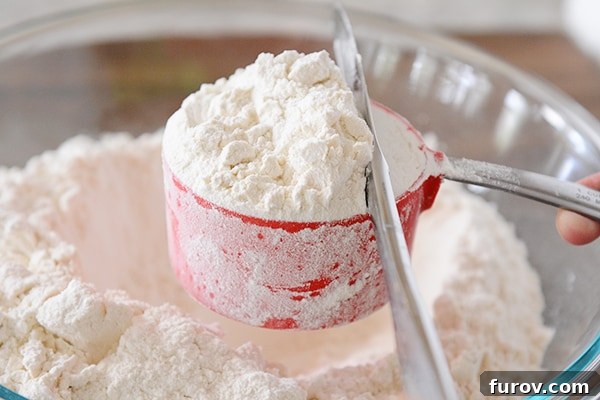 A butter knife leveling off a cup of flour. 