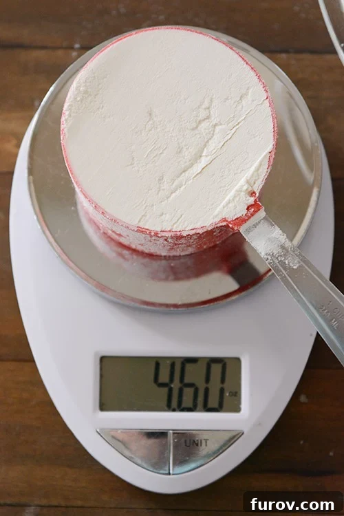 A red measuring cup full of flour on a kitchen scale. 