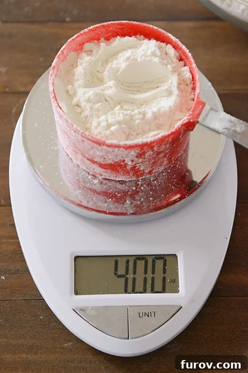 A digital kitchen scale measuring a partially filled measuring cup of flour. 
