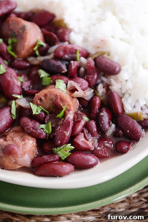 Hearty Slow Cooker Red Beans and Rice with Chicken Sausage 4 A white plate of cooked chicken sausage and red beans next to cooked white rice.
