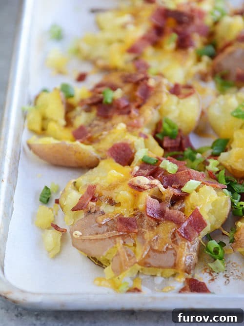 Ultimate Cheesy Bacon Garlic Smashed Reds 2 A cookie sheet full of perfectly golden-brown, cheesy bacon, and garlic butter smashed red potatoes, ready to be served as the ultimate side dish.