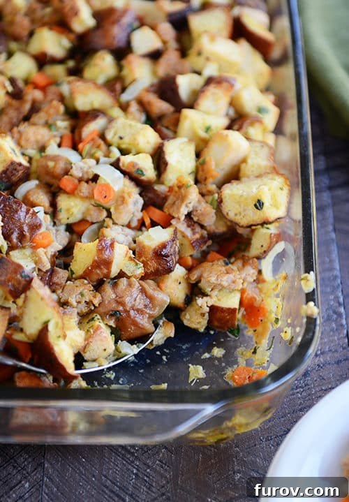 Savory Pretzel Sausage Stuffing 2 Top view of a glass dish full of pretzel roll and sausage stuffing, garnished with fresh herbs.