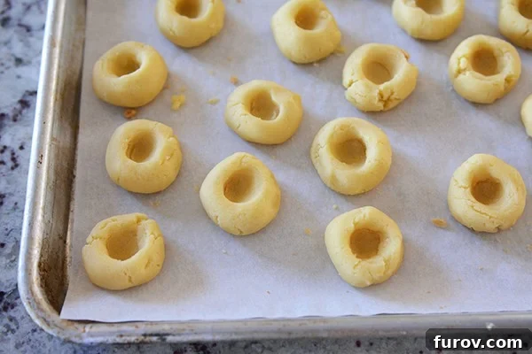 Caramel Chocolate Shortbread Delights 6 A cookie sheet of uncooked shortbread cookies with imprints in the middle.