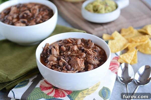 Two pristine white bowls, generously filled with steaming pressure cooker chicken and black bean chili, artfully presented and ready for enjoyment.