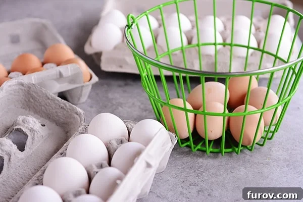 A visually appealing arrangement of raw eggs in various cartons and a green basket, showcasing different sizes.