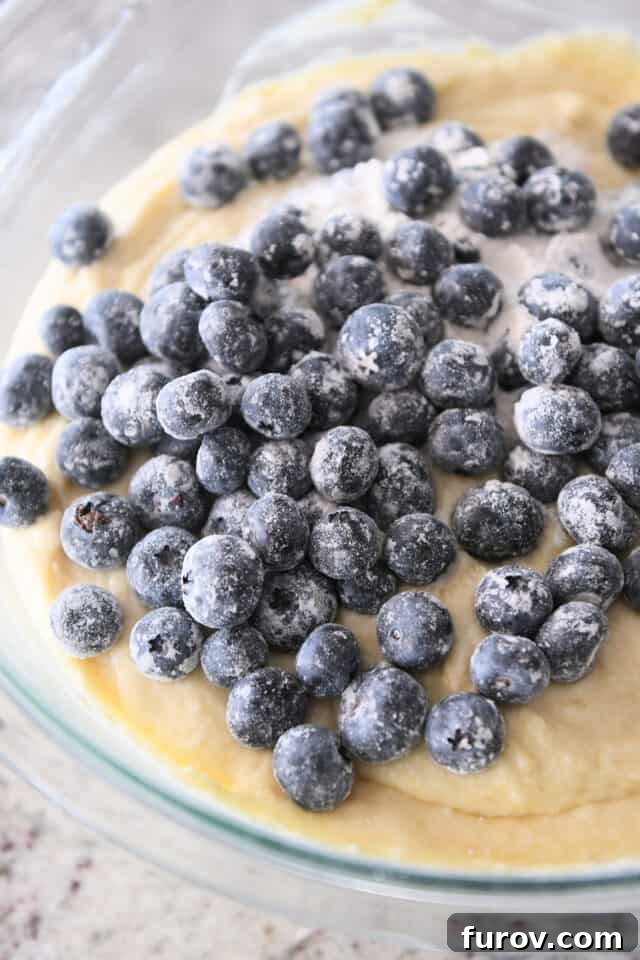 Lightly floured blueberries in a bowl, ready to be incorporated into the cake batter, ensuring even distribution.