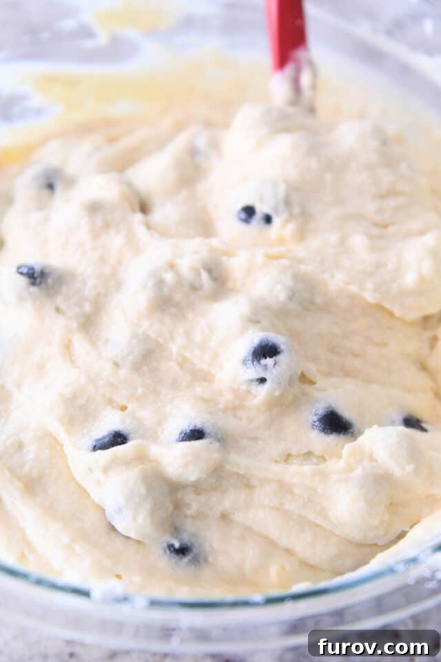Smooth, pale yellow lemon blueberry cake batter resting in a large glass bowl, ready for baking.