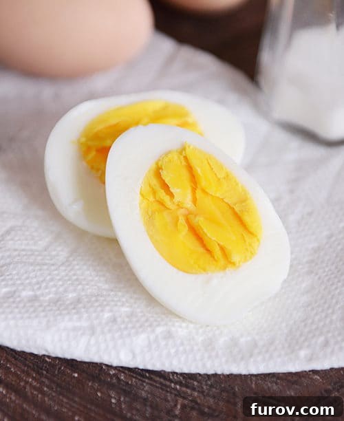 A meticulously sliced hard-boiled egg resting on a pristine white napkin, highlighting its creamy texture and flawless appearance.