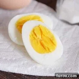 An appetizing image of a perfectly hard-boiled egg, cut in half, showcasing its firm white and creamy yellow yolk.