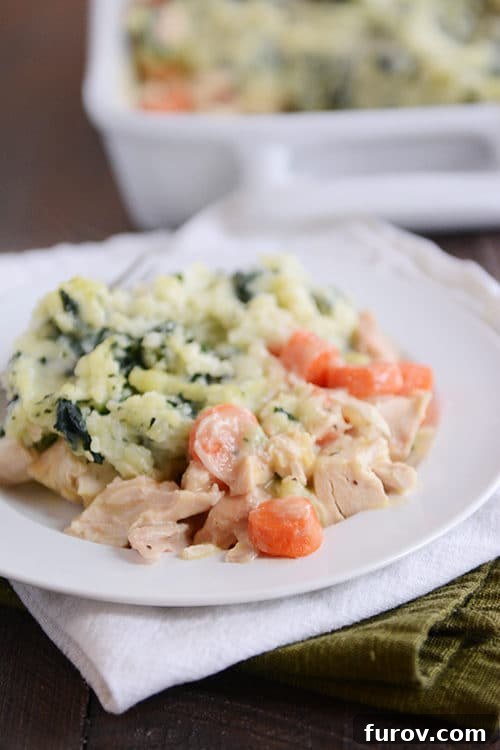 A creamy chicken and vegetable mixture next to kale-filled mashed potatoes.