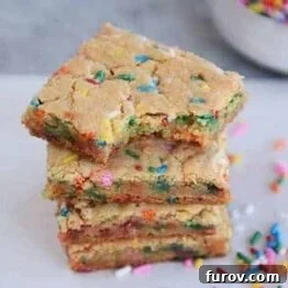A stack of thin and chewy funfetti blondie bars with rainbow sprinkles.