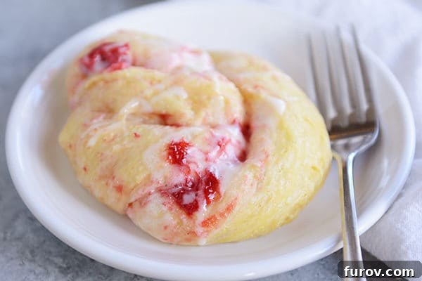 A single strawberry cream cheese roll on a white plate, with a fork resting beside it.
