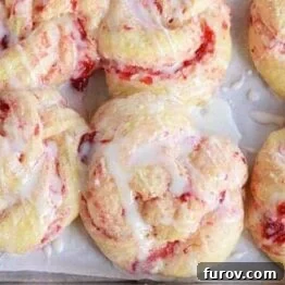 A close-up of a finished overnight strawberry cream cheese sweet roll with glaze.