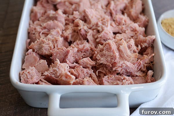 Sweet Glazed Ham in the Instant Pot 5 A white dish full of shredded, baked ham.