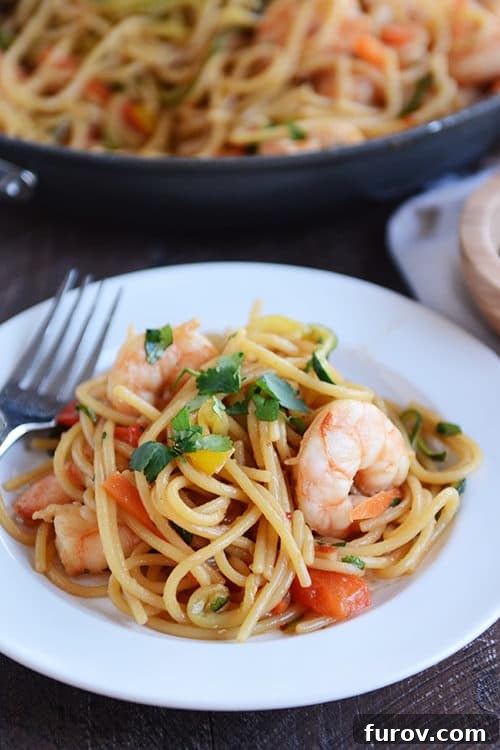 Fast Asian Garlic Noodles with Your Choice of Shrimp or Chicken 3 A beautifully plated serving of Asian garlic noodles, adorned with vibrant bell peppers, zucchini, carrots, and succulent shrimp, garnished with fresh cilantro, ready to be enjoyed.