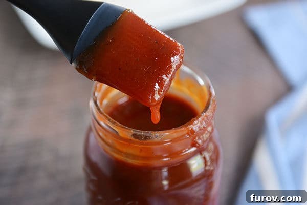 The Secret to Irresistible Homemade Barbecue Sauce 4 A mason jar full of BBQ sauce, with a drip coming down the side and a pastry brush with sauce over the top.