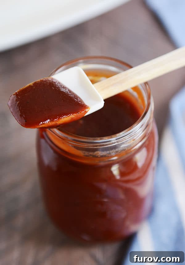 The Secret to Irresistible Homemade Barbecue Sauce 5 A mason jar full of BBQ sauce with a rubber spatula with sauce on it laying on the top.