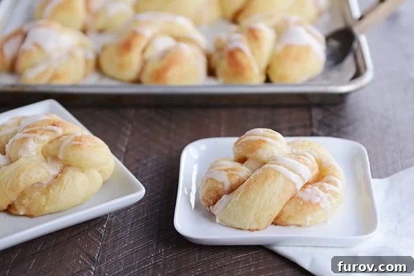 Golden-brown cinnamon twists drizzled with sweet white frosting, arranged on small white plates, with more twists visible in a baking pan in the background.
