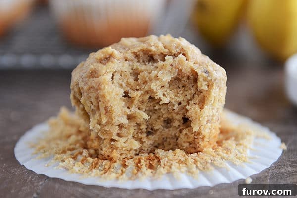 Wholesome Peanut Butter Banana Honey Muffins 3 A delicious whole grain peanut butter banana muffin on a white liner with a bite taken out, revealing its moist interior.