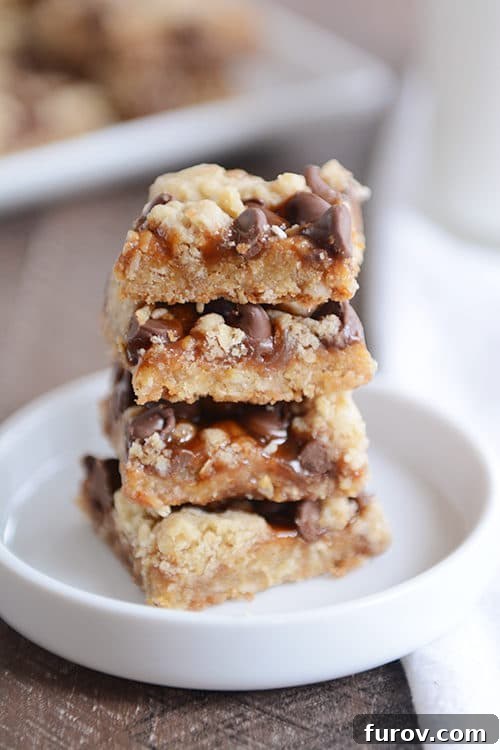 Gooey Chocolate Chip Caramel Cookie Bars 3 Four stacked up caramel chocolate chip cookie bars on a small round plate.