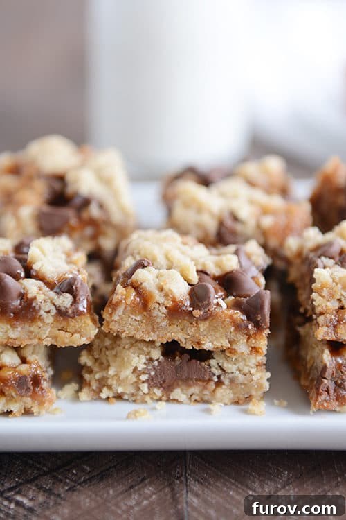 Gooey Chocolate Chip Caramel Cookie Bars 4 Squares of cut up caramel chocolate chip cookie bars on a white platter.