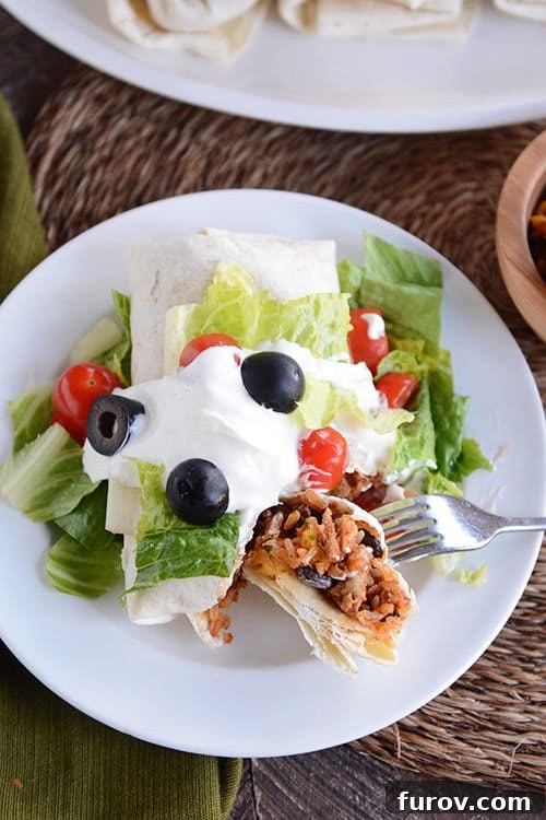 Wholesome Turkey and Brown Rice Taco Burritos 2 A turkey and rice burrito covered in toppings getting a bite taken out with a fork.