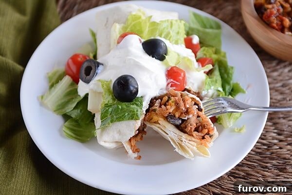 Wholesome Turkey and Brown Rice Taco Burritos 4 A ground turkey and rice burrito with toppings on a white plate.