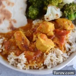 A top-down view of a bowl of Pressure Cooker Chicken Coconut Curry, garnished with fresh herbs and served alongside rice.