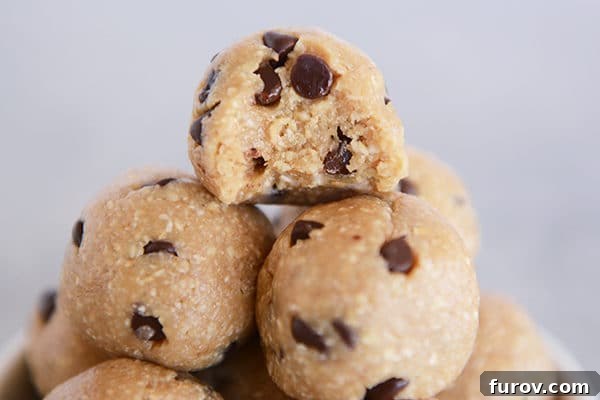 A stack of chocolate chip cookie dough bites, with a bite taken out of the top one revealing its soft interior.