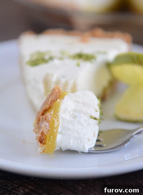 Zesty Key Lime White Chocolate Cheesecake Indulgence 2 A perfectly sliced Key Lime White Chocolate Cheesecake Pie, revealing its creamy layers and a hint of the graham cracker crust. A fork has just taken a delightful bite.