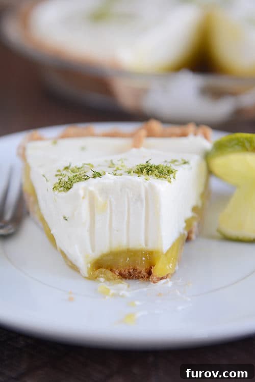Zesty Key Lime White Chocolate Cheesecake Indulgence 4 A close-up shot of a Key Lime White Chocolate Cheesecake Pie slice with a bite taken, highlighting the layered perfection and inviting texture.