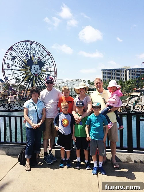 A family taking a picture in front of Mickey Mouse ferris wheel at Disneyland.