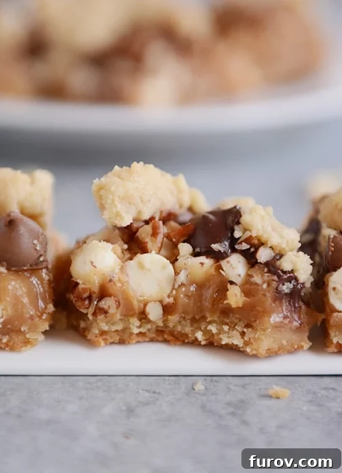 Delicious Caramel Pecan Chocolate Chip Toffee Bars, one with a bite taken out, showcasing the gooey layers.