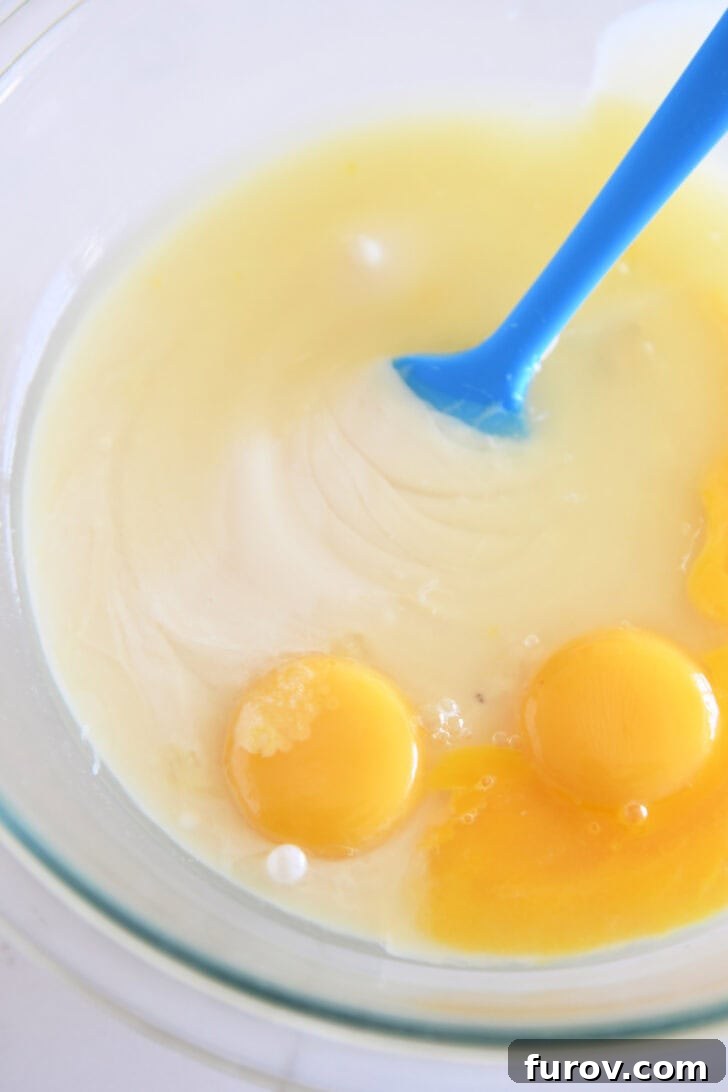 Top down view of a glass bowl with a lemon filling and raw eggs.