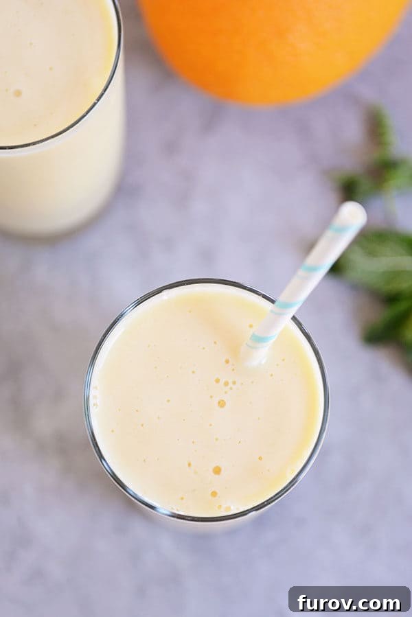 Top-down view of a creamy orange dreamsicle smoothie in a glass cup with a straw, beautifully presented and ready to enjoy.