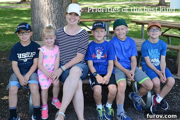 Taming the Back to School Bedlam 6 A mother and five children smiling and sitting together on a wooden picnic bench.