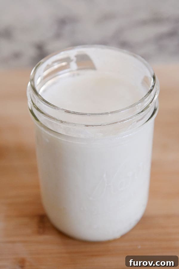 A mason jar filled with strained milk kefir, ready for consumption or a second fermentation, showcasing its smooth, creamy texture.