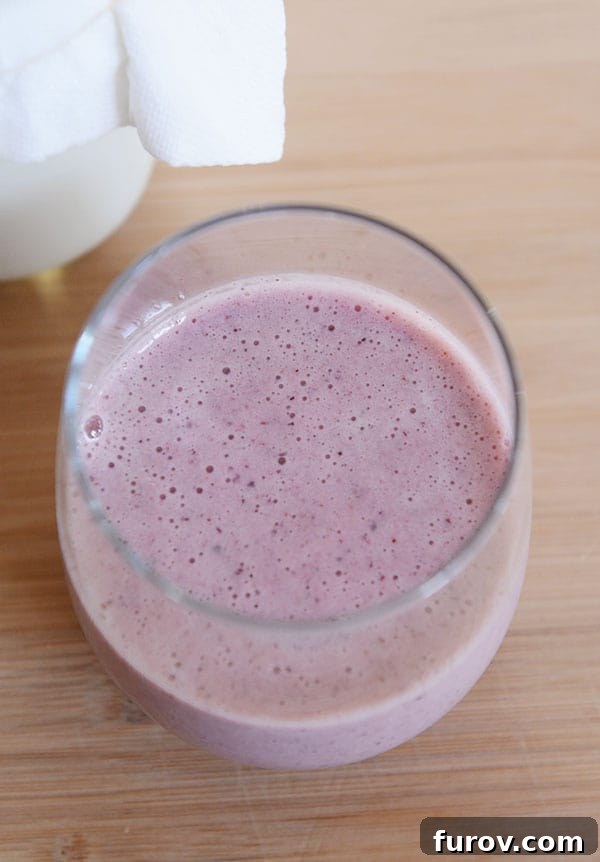 Top-down view of a vibrant purple berry kefir smoothie in a glass, garnished with fresh berries, highlighting its delicious and healthy appeal.