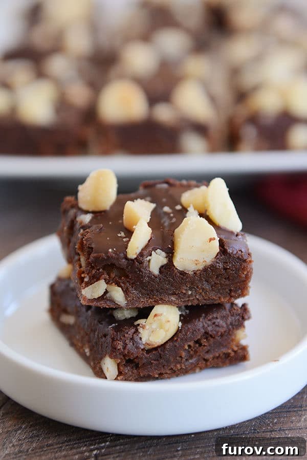 Two perfectly stacked chocolate macadamia brownies nestled in a small white ramekin, ready to be enjoyed.