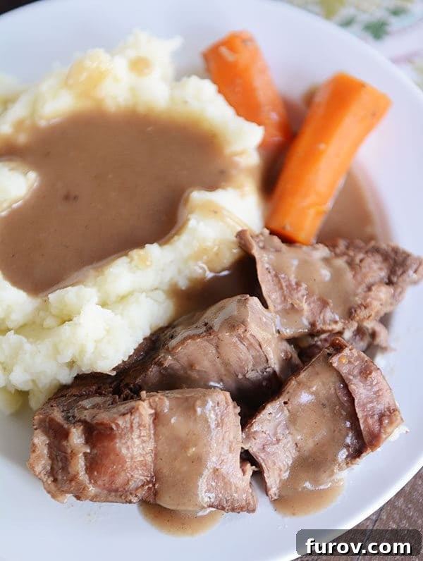 Melt-in-Your-Mouth Pot Roast and Savory Gravy 2 Top view of mashed potatoes, carrots, and roast covered with gravy. A generous serving of comfort food ready to be enjoyed.
