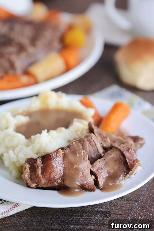Melt-in-Your-Mouth Pot Roast and Savory Gravy 7 A beautifully plated dish of pot roast with rich gravy, creamy mashed potatoes, and tender carrots, ready to be served.