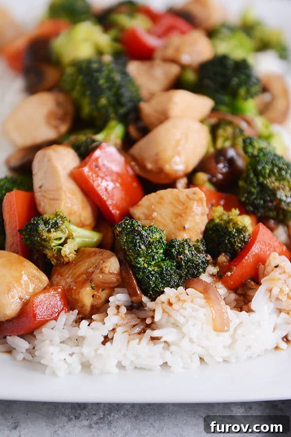 Chicken and vegetable stir-fry over cooked white rice. 