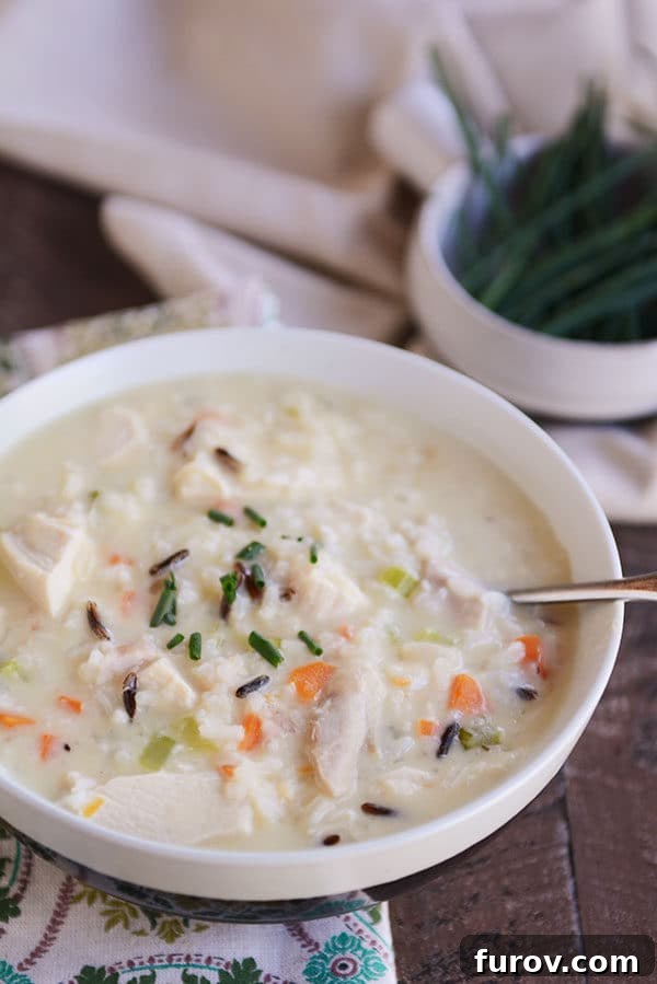 A full white bowl of creamy chicken and wild rice soup, inviting and ready to be enjoyed.