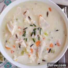 Top view of a white bowl of chicken, veggie, and wild rice soup.