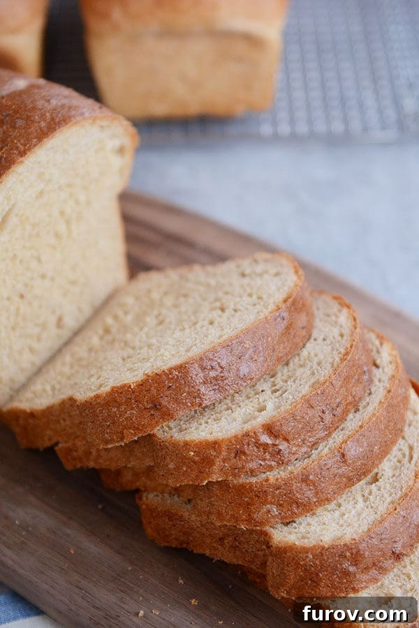 A loaf of wheat bread with thick slices cut off of it on a wooden cutting board.