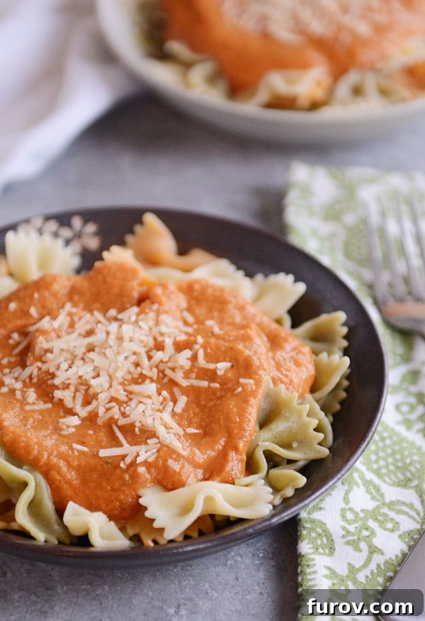 A beautifully plated bowl of bowtie pasta generously coated with creamy harvest sauce and garnished with fresh parmesan cheese, ready to be enjoyed.